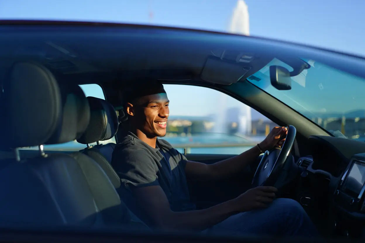 Homme souriant dans une voiture devant le jet d'eau de Genève